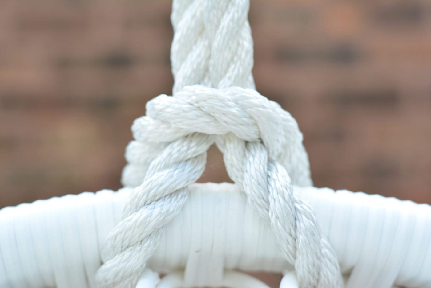 Close up of a white rope tied to a hanging chair.