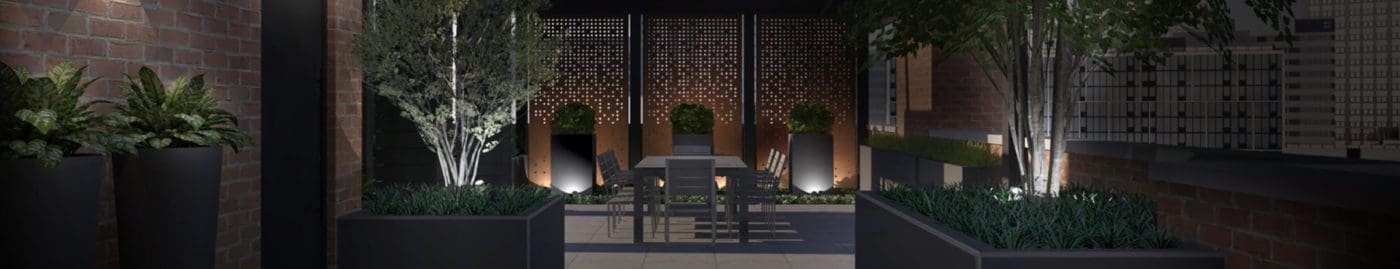 Outdoor patio at night with landscape lighting.