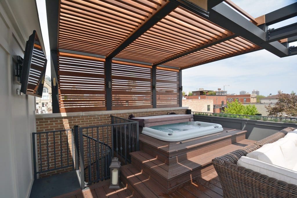Outdoor hot tub spa covered by a wood and metal pergola.
