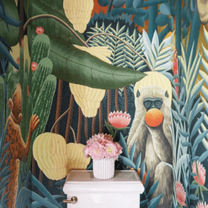 Jungle style wallpaper in a bathroom on the wall behind a toilet.
