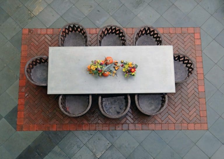Overhead view of a bluestone paved patio area with a patio table and various potted plants.