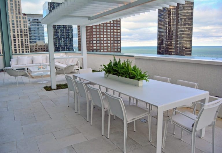 Outdoor white dining furniture on a roof deck in the city.