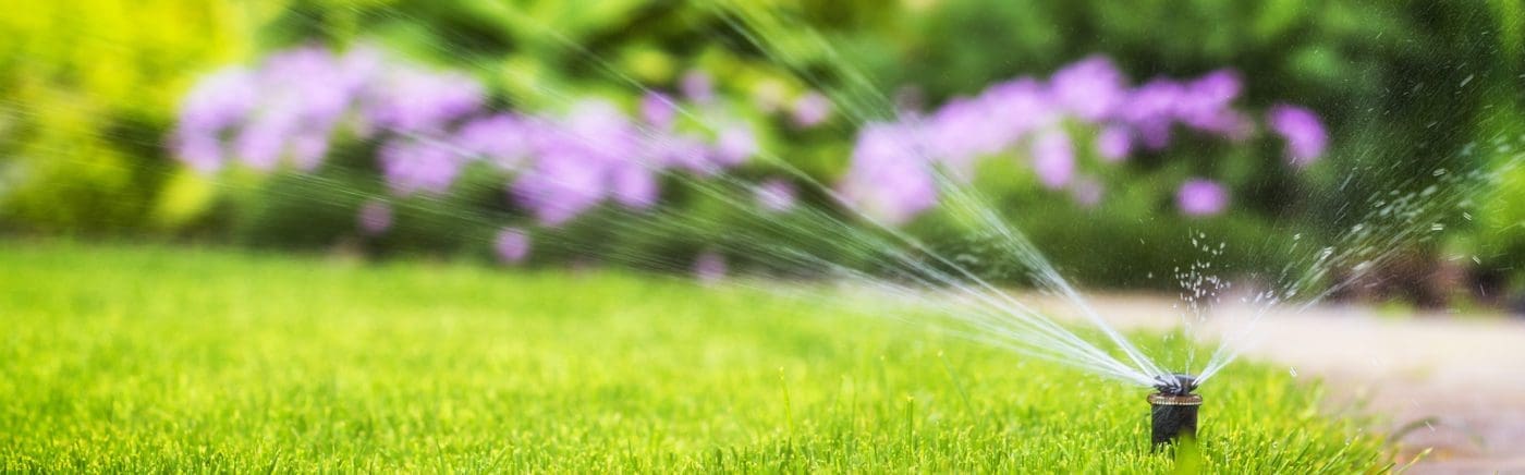 Close up of an automatic sprinkler system watering the lawn on a background of green grass.