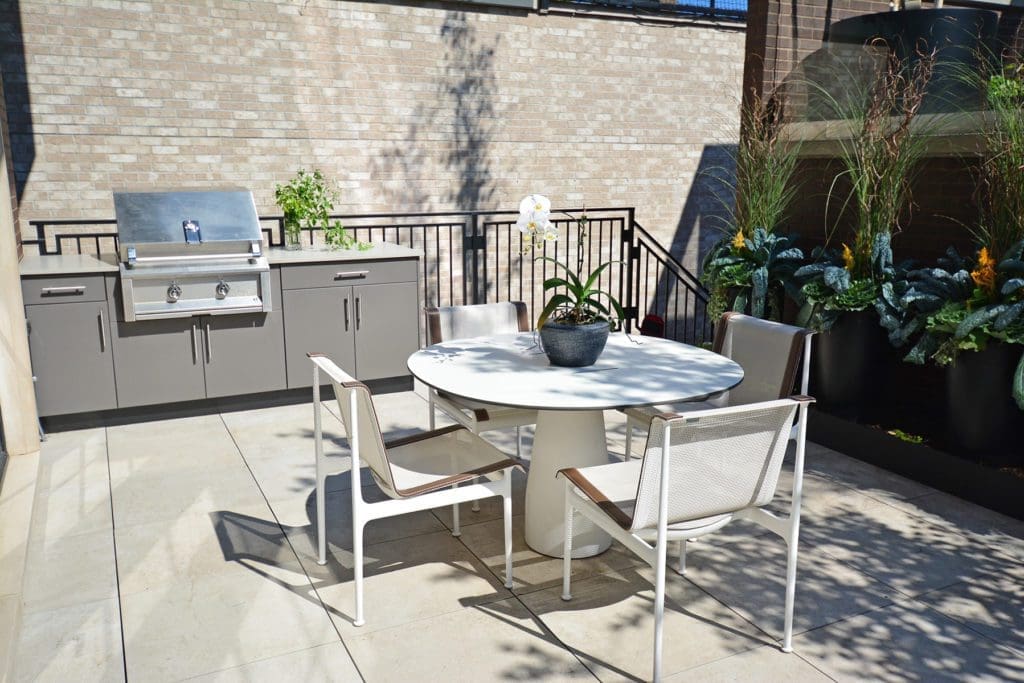 An outdoor kitchen on a deck with a small round table.