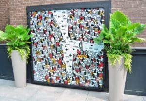 Graphic artwork displayed on an outdoor patio between large planters.