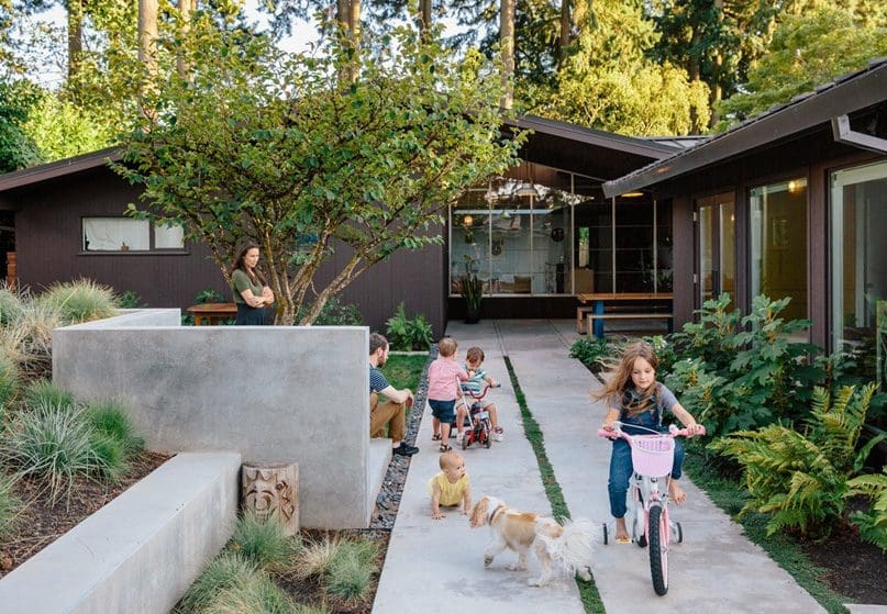 Outdoor paved path with kids riding bikes outside of their home.