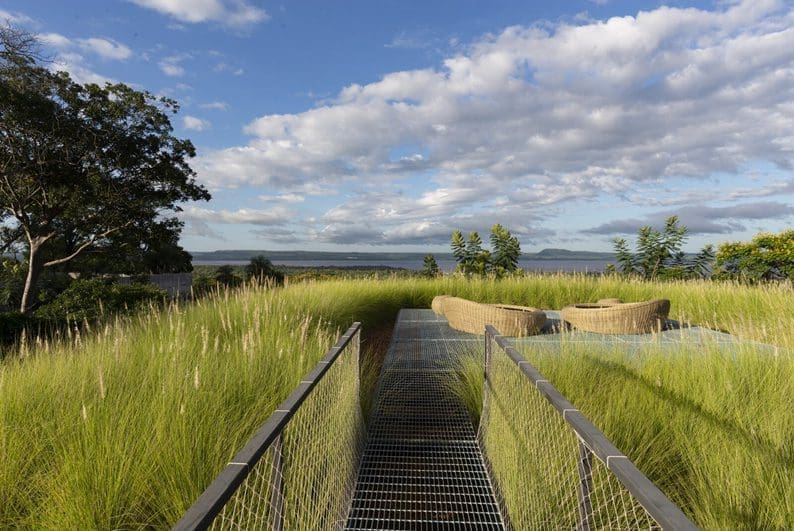Elevated walkway leading to a relaxed seating area near a marsh.