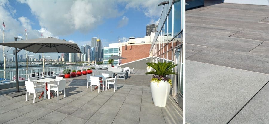 Multiple outdoor tables with umbrellas on a roof deck overlooking the water.