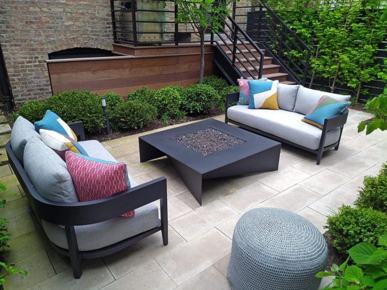 Patio area with square gas firepit in the middle of two outdoor couches.
