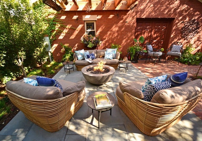Round gas fire pit with seating area shaded by a pergola.