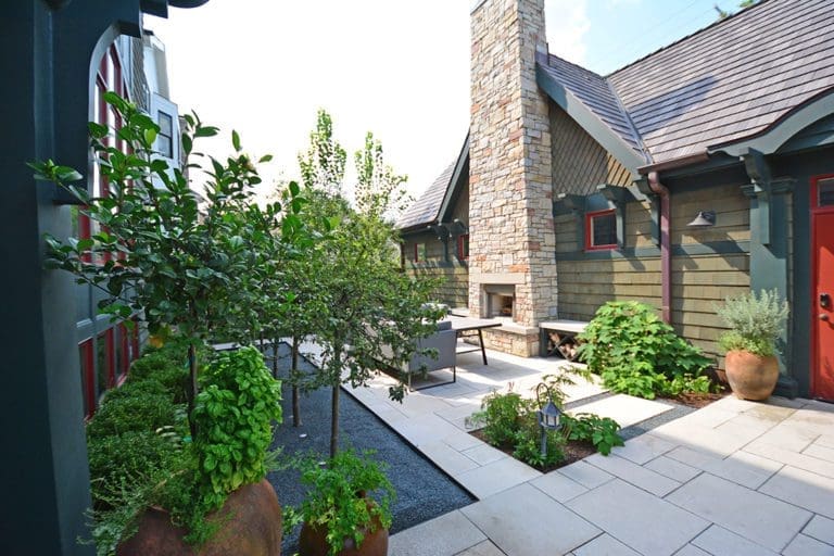 Outdoor fire place with various small trees and plantings around it.