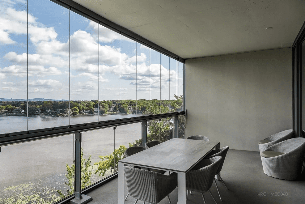 Covered balcony with dining table and glass enclosure.