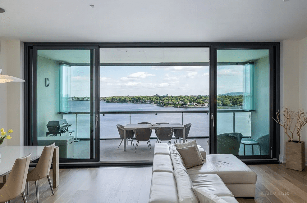 Outside view of covered balcony with dining table and glass enclosure.